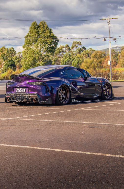 Purple widebody Toyota Supra in an empty car park at golden hour